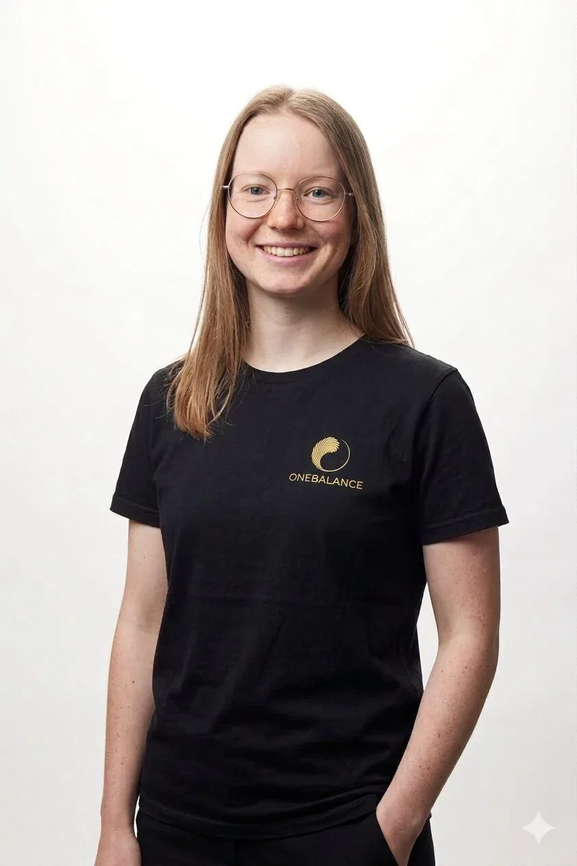 Portrait von ONEBALANCE Physiotherapeutin Isabel Kronenwett im schwarzen ONEBALANCE-Shirt vor hellem Hintergrund