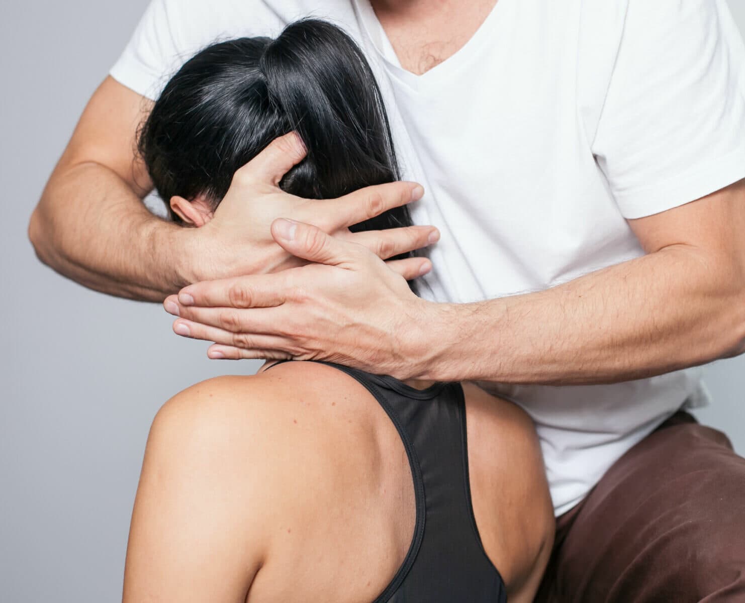 Therapeut führt eine manuelle Nackenbehandlung bei einer Patientin durch, zur Linderung von Verspannungen und Schmerzen.